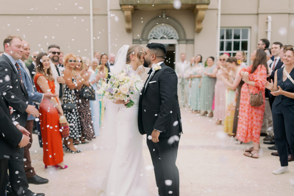 Newlyweds embracing in countryside setting, luxury wedding photography by Camilla Joy
