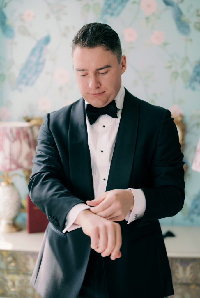 Groom Cillian in classic black tuxedo with suspenders and bow tie for London wedding