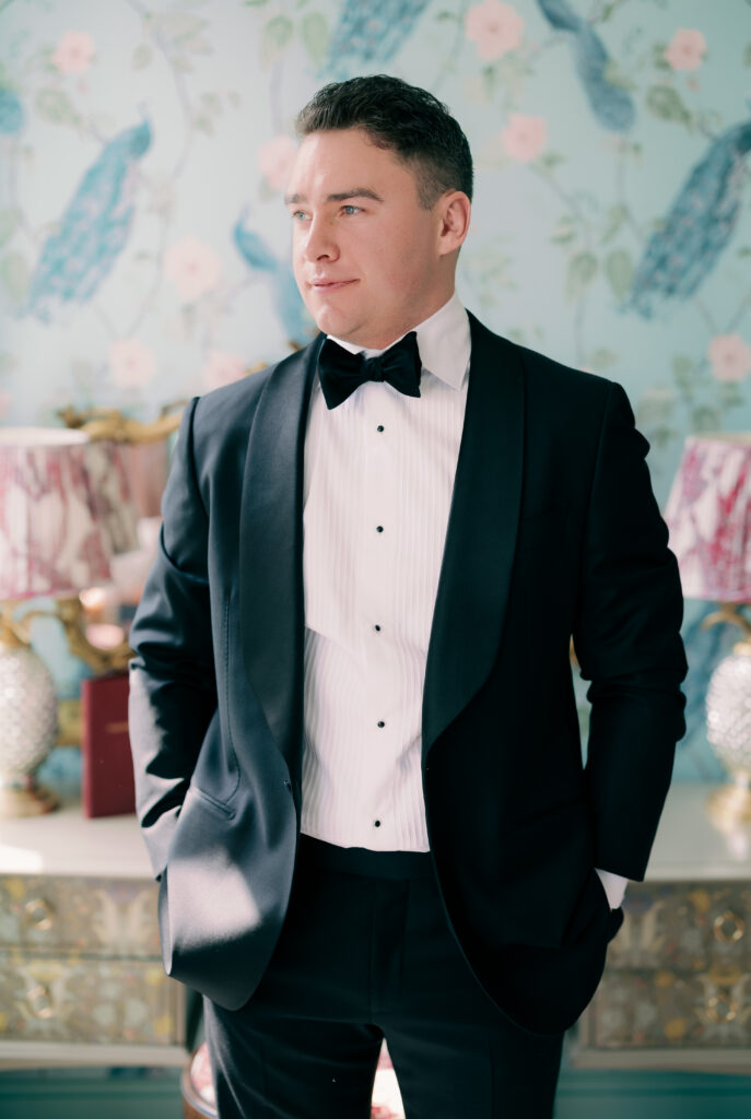 Dapper groom portrait against colorful wallpaper backdrop in London